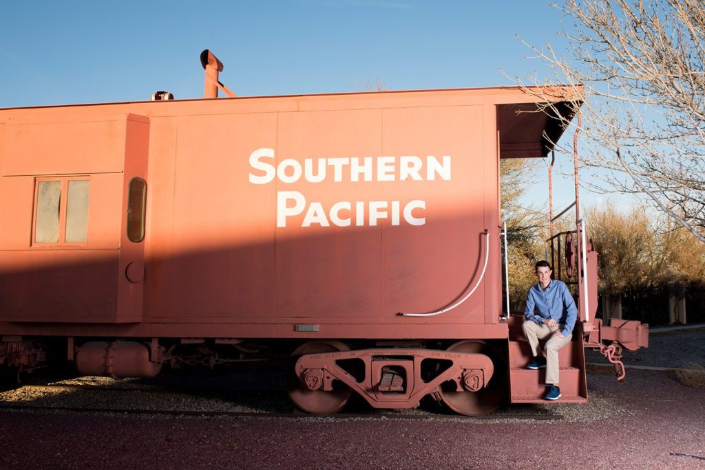 high-school-senior-boy-in-front-of-orange-southern-pacific-train-car