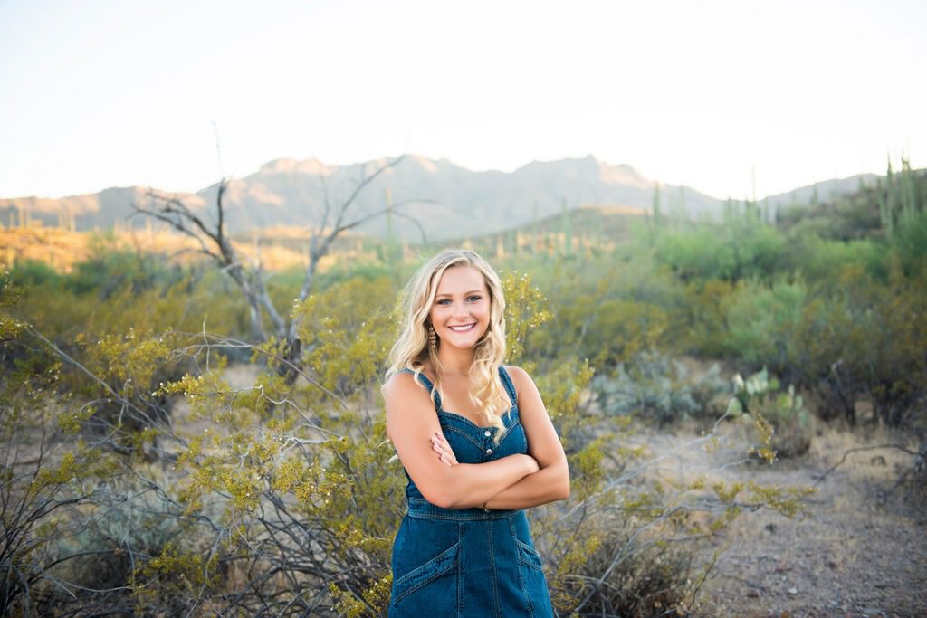 high school senior standing with arms crossed near creosote