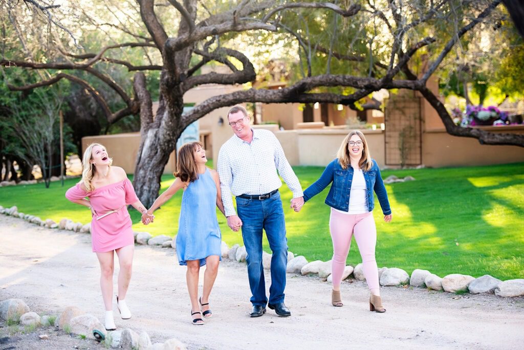 family walking and laughing along dirt road with green grass in the background