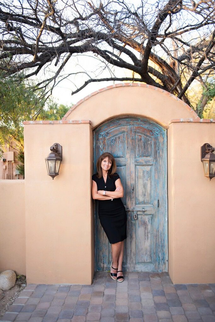 Tucson realtor leaning against old turquoise doorway.