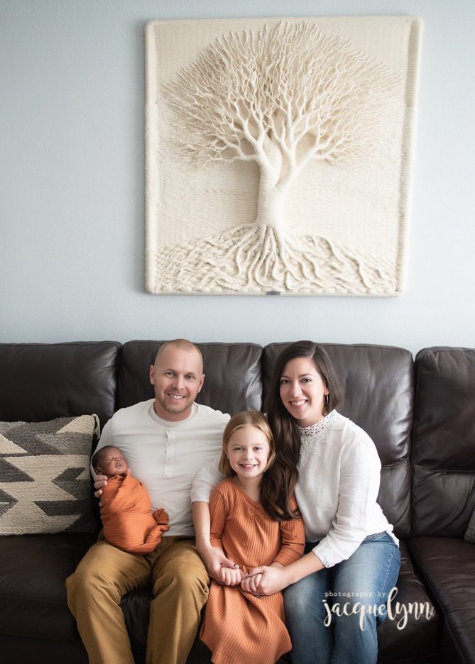 family of four with their newborn son that they adopted and their older daughter wearing orange, cream, brown and blue