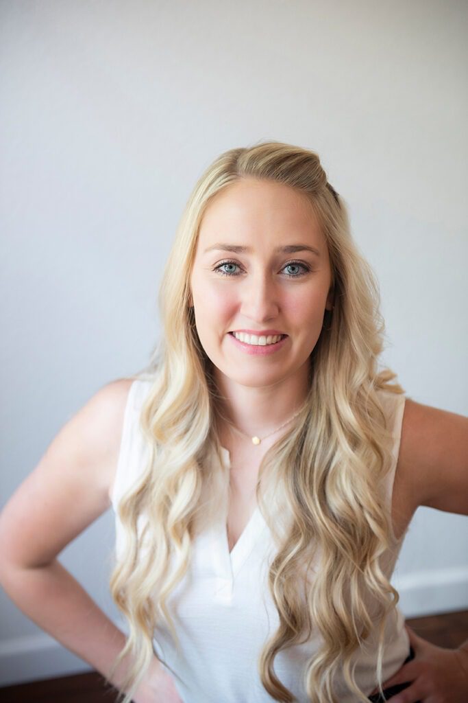 blond woman with blue eyes posing with hands on hips for headshot session