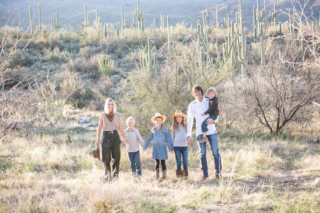 morning at tanque verde ranch tucson family photo session family walking through the desert after sunrise