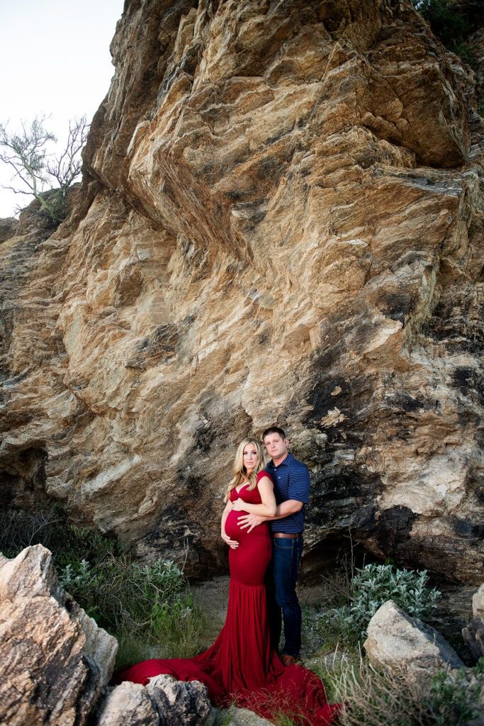 dramatic tucson maternity photo of pregnant woman in red dress and man by rocks