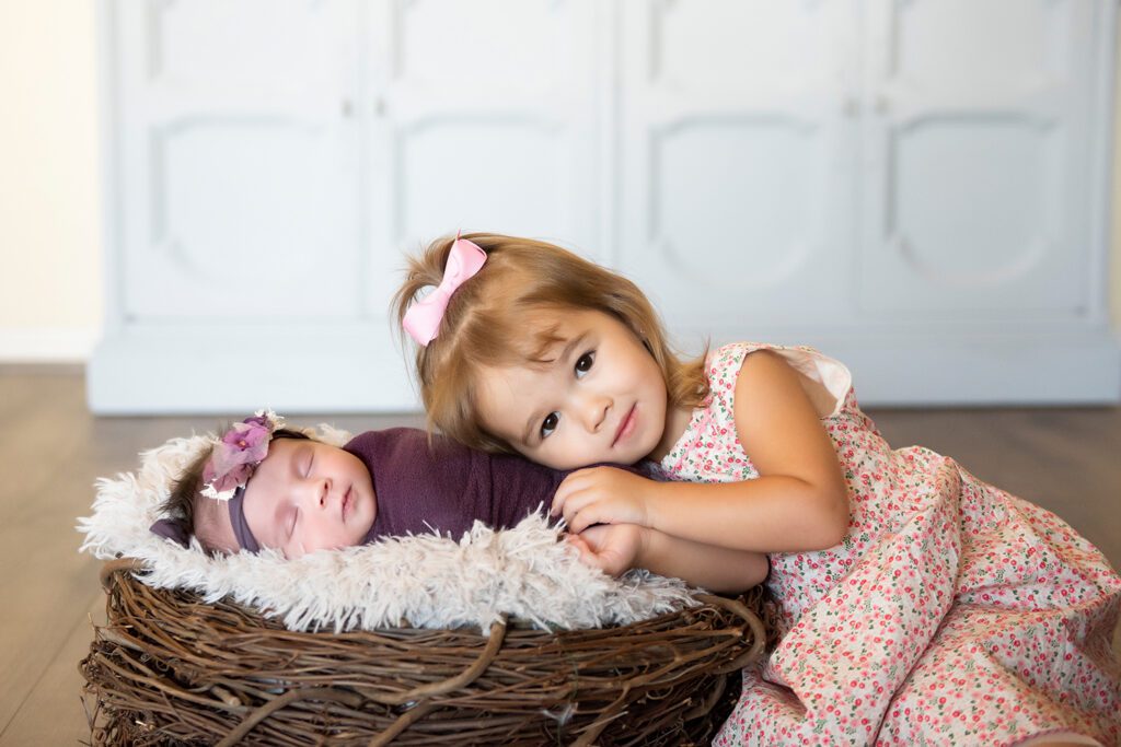 baby girl in purple for newborn photo with older sibling